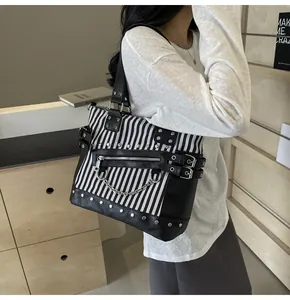 Detail shot of black and white striped tote bag with punk metal rivets and chains