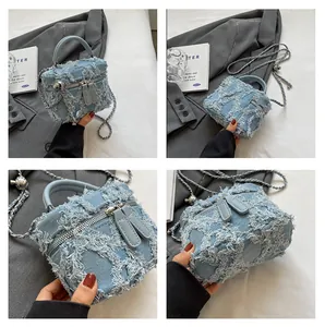 Detailed close-up of light blue distressed denim crossbody bag with frayed edge patches