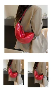 Detail of red crescent shoulder bag with knotted strap and glossy canvas finish