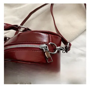 Detailed close-up of dark red PU leather bag with silver hardware and pearl pendant