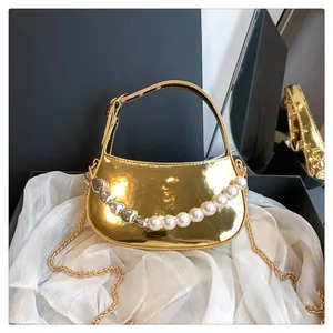 Dettaglio mini borsa dorata con perle e cuori in una confezione regalo di lusso