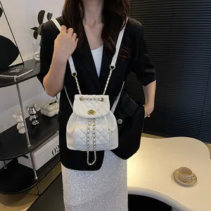 White quilted mini backpack with gold chain straps and turn-lock closure on model