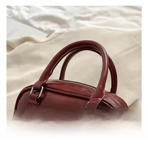 Detailed view of deep red PU handbag with dual handles and elegant pearl heart charm
