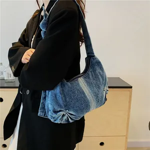 Pleated denim shoulder bag in washed blue worn by model with casual styling