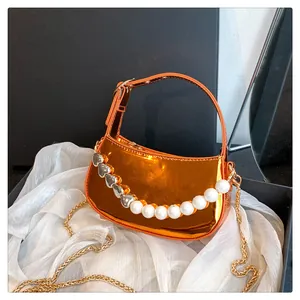 Dettaglio della mini borsa arancione metallizzato con catena decorativa di perle e cuori