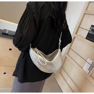 Detail of silver metallic crescent bag with unique knot shoulder strap and sleek finish