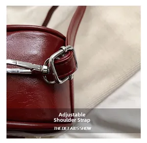 Close-up of adjustable strap with silver buckle on wine red leather handbag