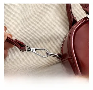 Detail of premium silver metal hardware hook on dark red PU leather shoulder bag