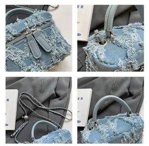 Detail of light blue denim bucket bag featuring dual zippers and woven chain strap
