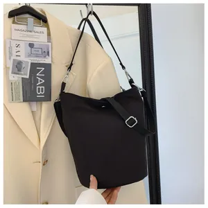 Detail of minimalist black bucket bag with nylon strap and silver metal hardware accents