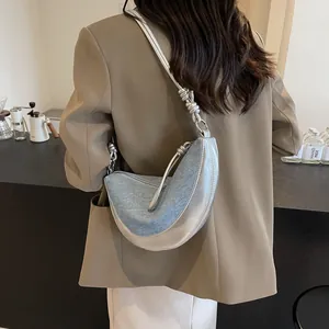 Metallic and denim crescent shoulder bag with knot strap detail shown on a model