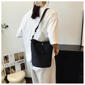 Detail view of the black minimalist bucket bag showing its sleek nylon texture and magnetic snap