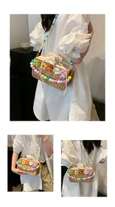Detail of woven straw crossbody bag with colorful knit flowers and beaded strap