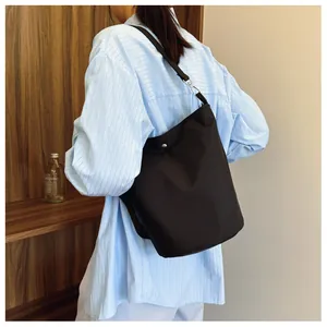 Detail of minimalist black nylon bucket bag showing silver snap closure and shoulder strap
