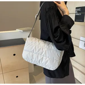 Détail d'un sac à bandoulière matelassé gris clair avec coutures horizontales et sangle