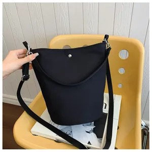 Close-up of black nylon bucket bag with silver magnetic buckle on a yellow chair
