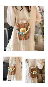 Detail of straw woven crossbody bag featuring colorful beaded strap and floral accent