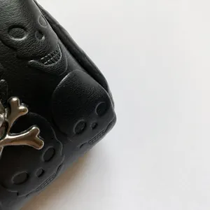 Λεπτομέρεια μαύρης τσάντας από τεχνητό δέρμα με ανάγλυφο νεκροκεφαλή και γοτθικό κούμπωμα