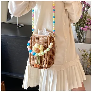 Detail of hand-woven straw crossbody bag with colorful bead strap and floral decor