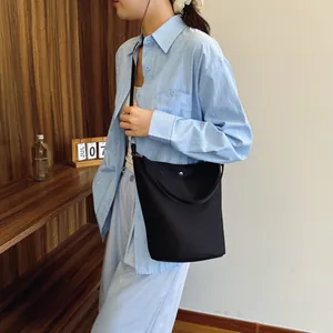 Minimalist black nylon bucket bag with silver snap button and slim shoulder strap for women