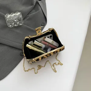 Leopard print evening clutch with gold metal frame and chain strap shown with essentials