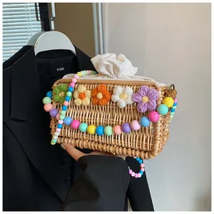 Detail of straw woven bag featuring colorful crochet flowers and beaded shoulder strap