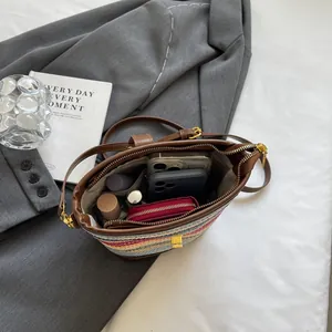 Rainbow striped woven bucket bag with leather strap and daily essentials inside