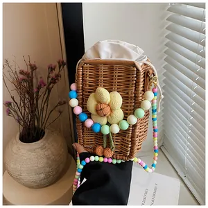 Detail of woven straw bucket bag featuring a fabric flower and colorful beaded strap