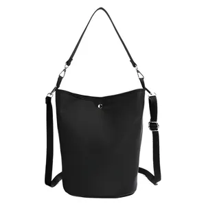 Minimalist black bucket bag with silver hardware and adjustable straps in a front view