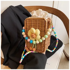 Detail of woven straw bag featuring a floral applique and colorful beaded shoulder strap