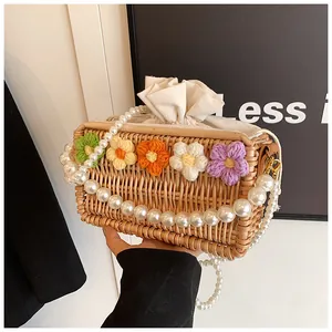 Detail of woven straw bag with colorful crochet flowers and large faux pearl handle
