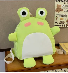 Detailansicht des grünen Frosch-Kinderrucksacks auf Holztisch mit warmer Dekoration