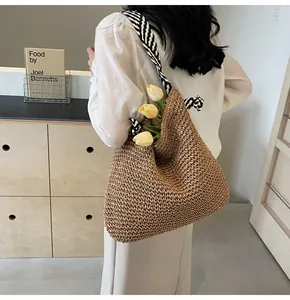 Detail of hand-woven straw shoulder bag with striped straps and spacious interior