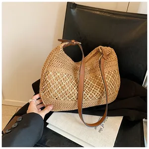 Detail of hand-woven straw tote with hollow-out pattern and brown leather strap