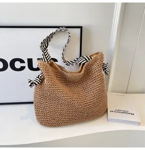 Close-up of woven straw bag texture with navy striped ribbon handle on white background