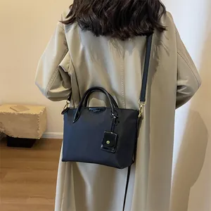 Lightweight black oxford tote bag with crossbody strap and small charm accessory