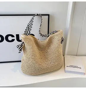 Detail of hand-woven beige straw bag featuring black and white striped fabric handles