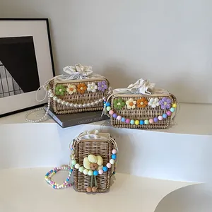 Three handmade straw crossbody bags featuring crochet flowers and beaded pearl straps