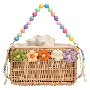 Handmade woven straw crossbody bag with colorful knit flowers and beaded handle strap