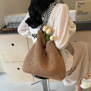 Handmade woven straw shoulder bag featuring a chic navy blue and white striped strap
