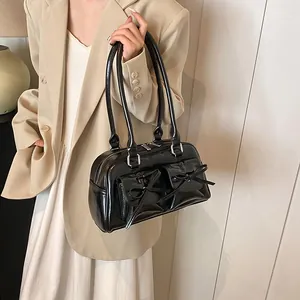 Glossy black PU leather bowling bag with bows and twin front pockets shown on model