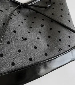 Close-up of herringbone fabric tote with black polka dots and sleek leather trim detail
