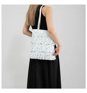 Dettaglio delle balze in pizzo floreale blu e strati di tulle della borsa bianca