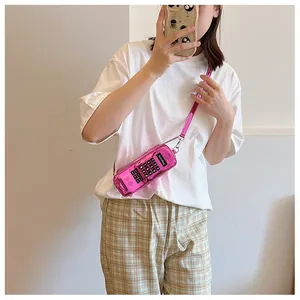 Close-up of a pink retro phone-shaped crossbody bag worn by a model in a casual outfit