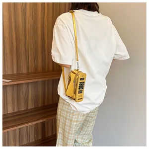 Macro view of a gold metallic telephone-shaped crossbody bag showing detailed dial design