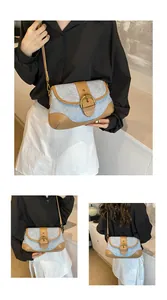 Detailed close-up of blue denim and brown leather stitching on a saddle crossbody bag