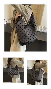 Detailed view of the grey polka dot tote bag with a black bow and reinforced bottom