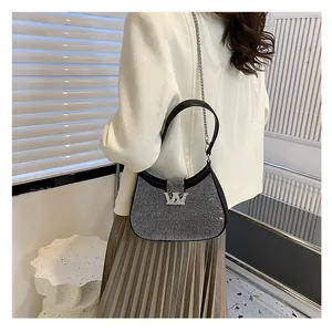 Detail of black rhinestone hobo bag with silver W buckle and chain strap on a model