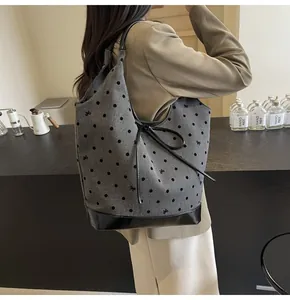 Detail of grey tote bag with black polka dots, bow patterns and leather trim accents