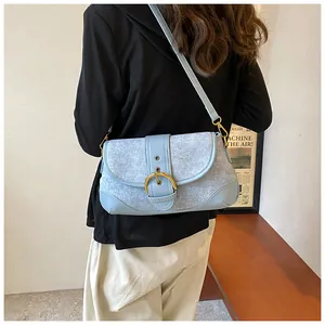 Detail showing light blue denim patchwork bag with a vintage golden horseshoe buckle